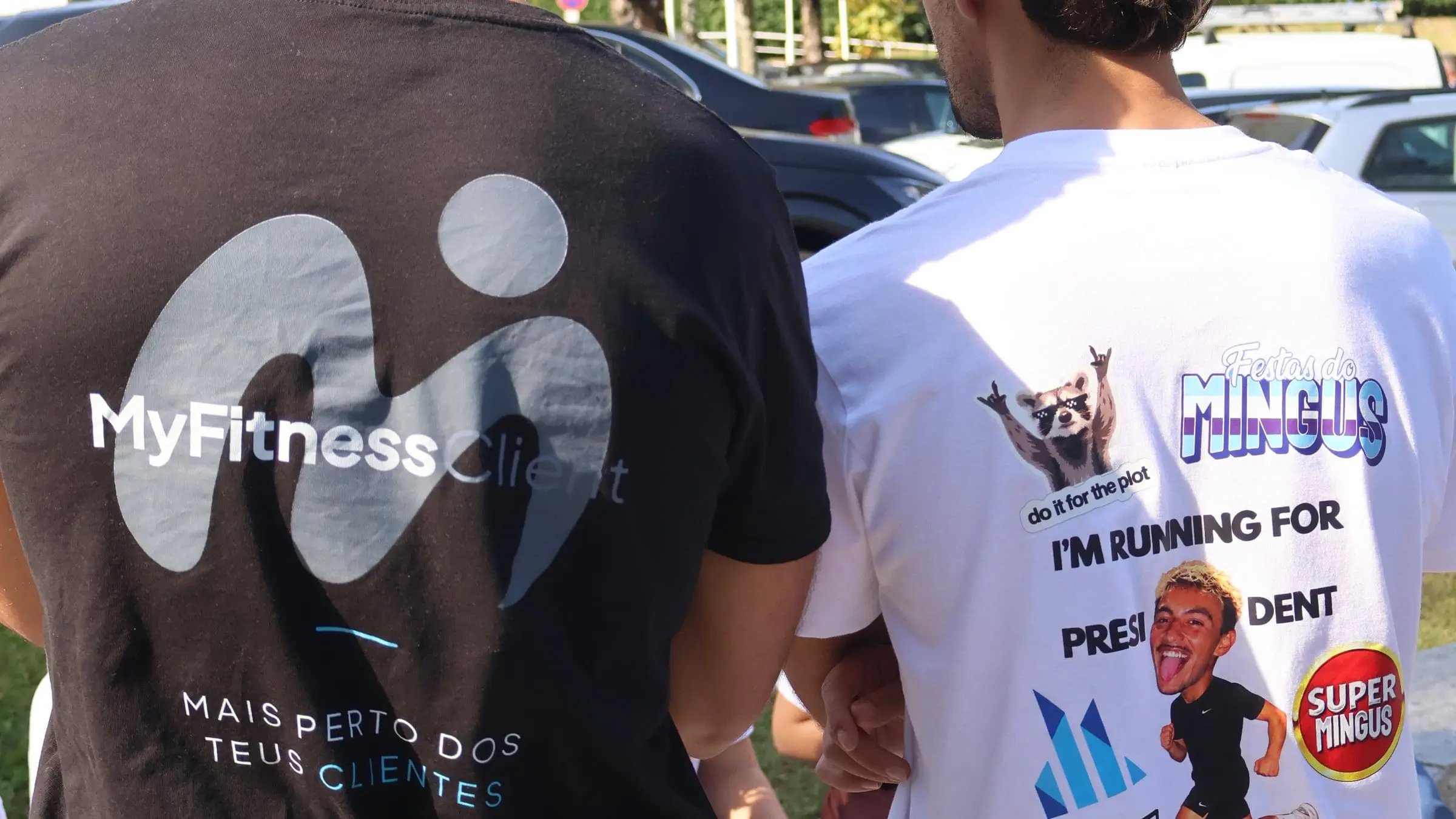 Two people seen from behind on the UMAIA campus, one in a MyFitnessClient T-shirt and the other in the Lista U candidate's campaign T-shirt